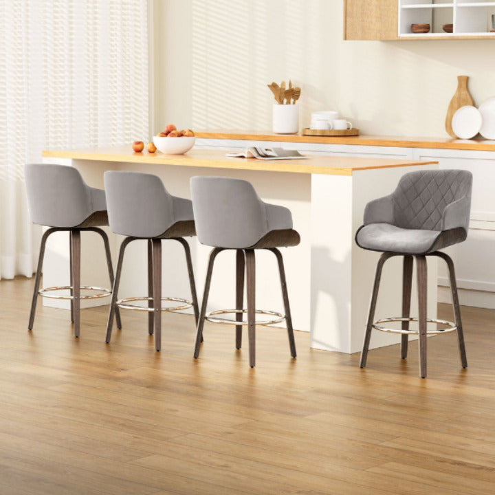 Set of 4 Aston 360-degree swivel bar stools in grey velvet and walnut finish arranged at a white kitchen island.