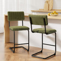 Set of 2 Orman cantilever bar stools in olive green velvet at a modern wooden kitchen breakfast bar.
